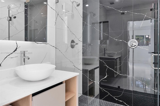 bathroom with vanity, a shower with door, and tile walls