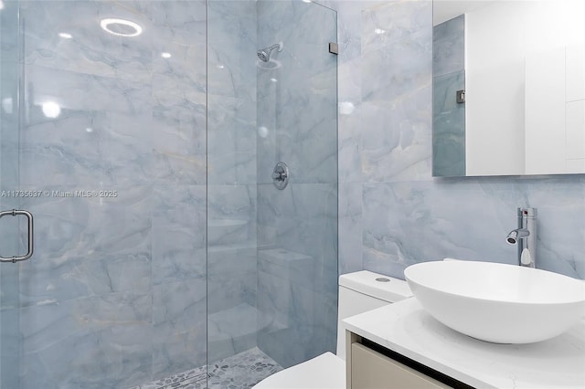 bathroom with tile walls, backsplash, vanity, walk in shower, and toilet