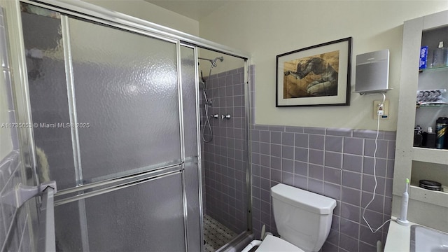 bathroom with toilet, a shower with door, and tile walls