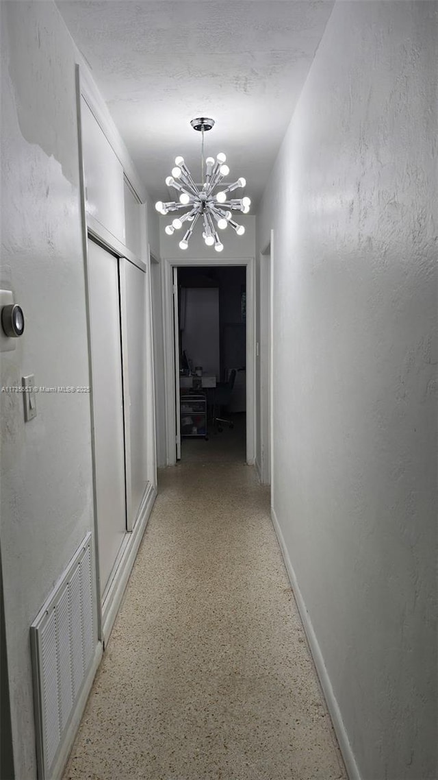 hall with an inviting chandelier and a textured ceiling