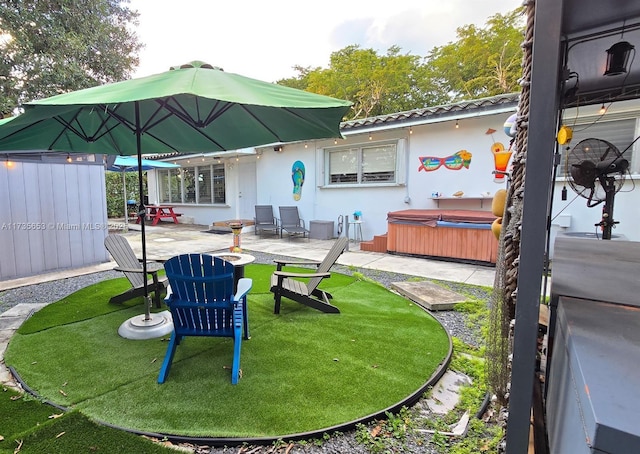 back of house with a patio area, a hot tub, and a lawn