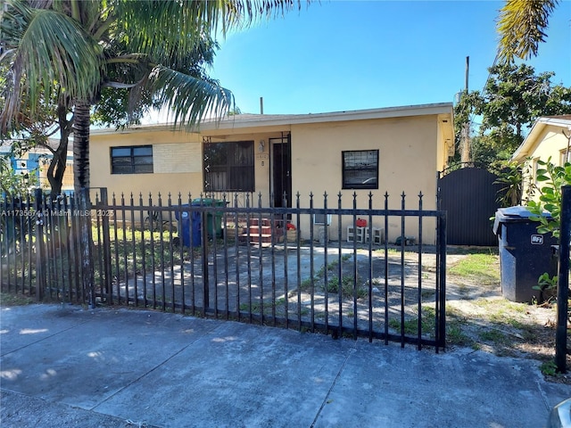 bungalow-style home featuring a gate, a fenced front yard, and stucco siding
