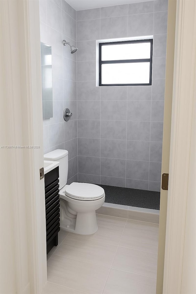 bathroom featuring tile patterned floors, toilet, and tiled shower