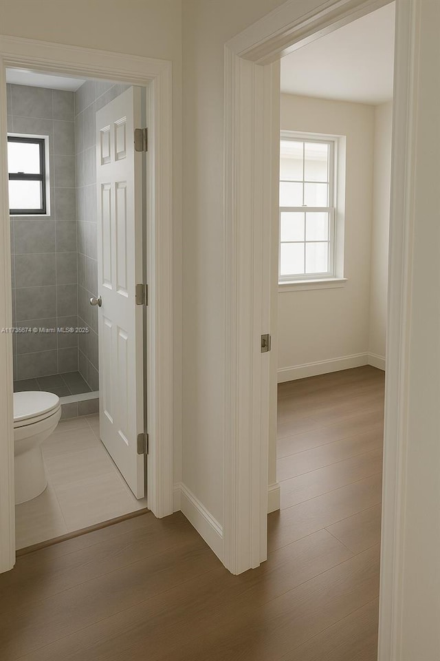 corridor with baseboards and wood finished floors