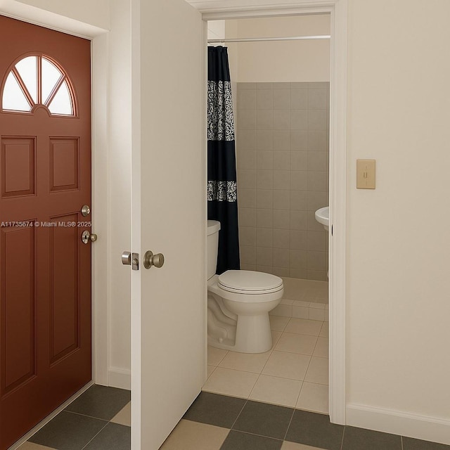 full bathroom with a tile shower, tile patterned floors, baseboards, and toilet