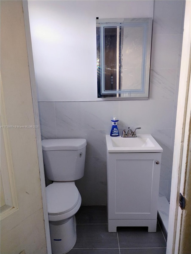 bathroom featuring toilet, vanity, tile patterned floors, and tile walls