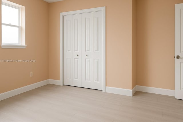 unfurnished bedroom with a closet and baseboards