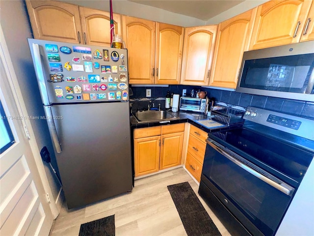 kitchen featuring light brown cabinetry, sink, light hardwood / wood-style flooring, and stainless steel appliances