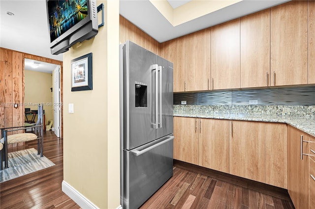 kitchen featuring light stone counters, dark hardwood / wood-style flooring, high end fridge, and light brown cabinetry