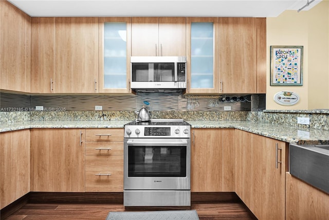 kitchen featuring stainless steel appliances, dark hardwood / wood-style floors, and light stone counters