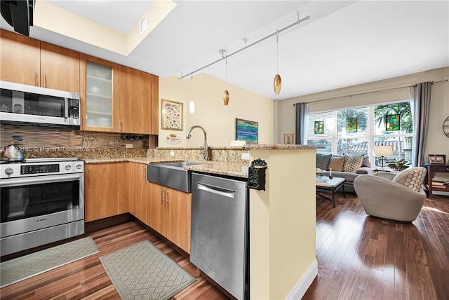 kitchen with stainless steel appliances, decorative light fixtures, light stone counters, and kitchen peninsula