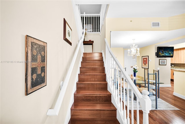 stairway featuring wood-type flooring and a notable chandelier