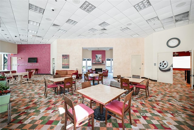 carpeted dining area with a towering ceiling and a paneled ceiling