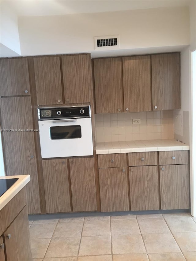 kitchen with backsplash, tile counters, and oven