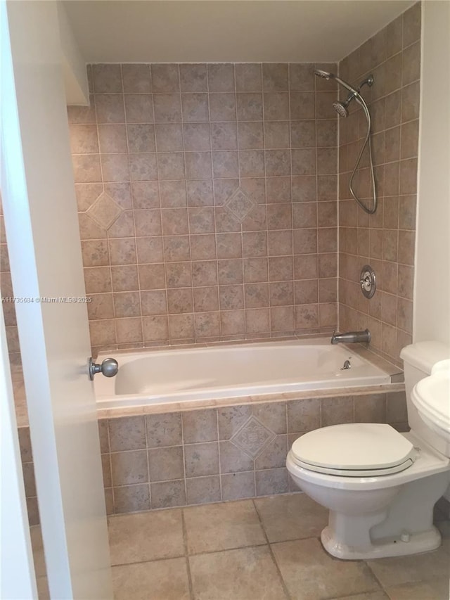 bathroom featuring tiled shower / bath combo, tile patterned floors, and toilet