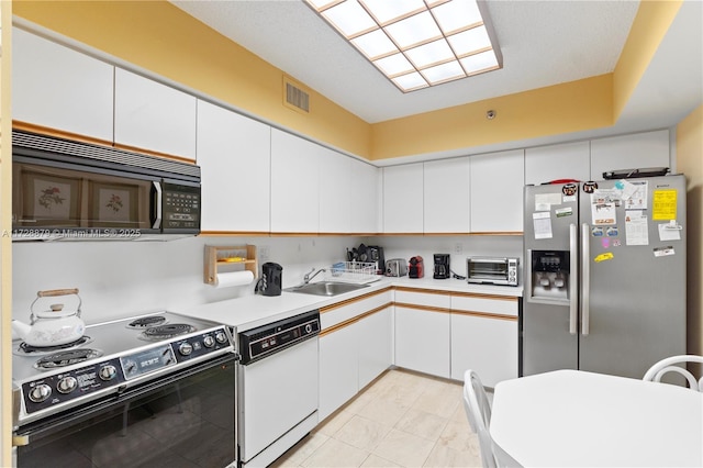 kitchen with white cabinets, light countertops, a sink, and black appliances