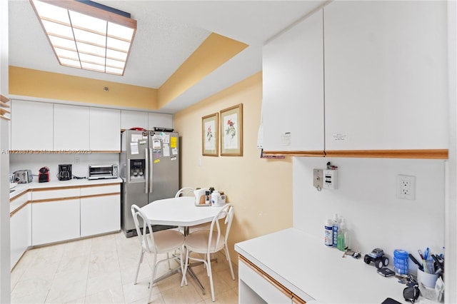 kitchen with white cabinets, a toaster, stainless steel refrigerator with ice dispenser, and light countertops