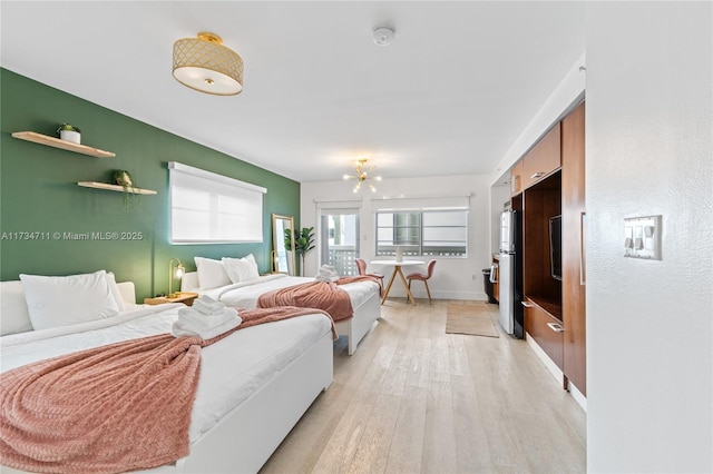 bedroom with refrigerator, a notable chandelier, and light wood-type flooring