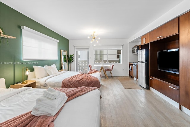 bedroom with an inviting chandelier, stainless steel refrigerator, and light hardwood / wood-style flooring