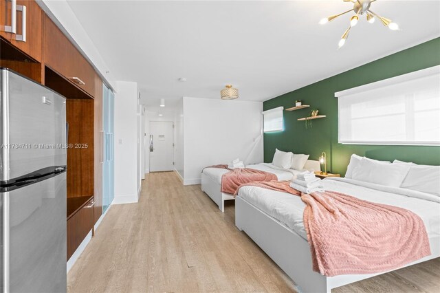 bedroom featuring stainless steel fridge and light hardwood / wood-style floors