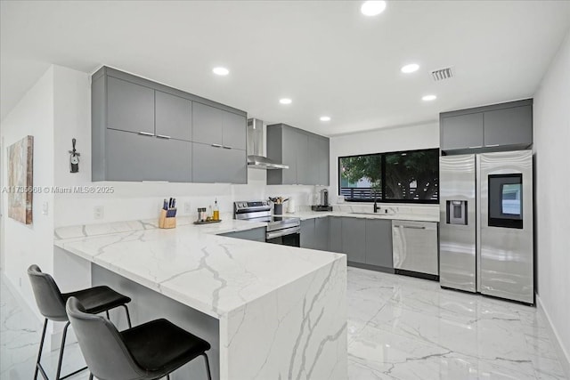 kitchen with sink, gray cabinetry, stainless steel appliances, a kitchen breakfast bar, and kitchen peninsula