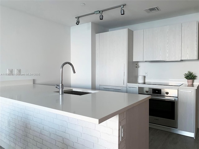 kitchen featuring a breakfast bar, sink, black electric cooktop, dark hardwood / wood-style floors, and oven