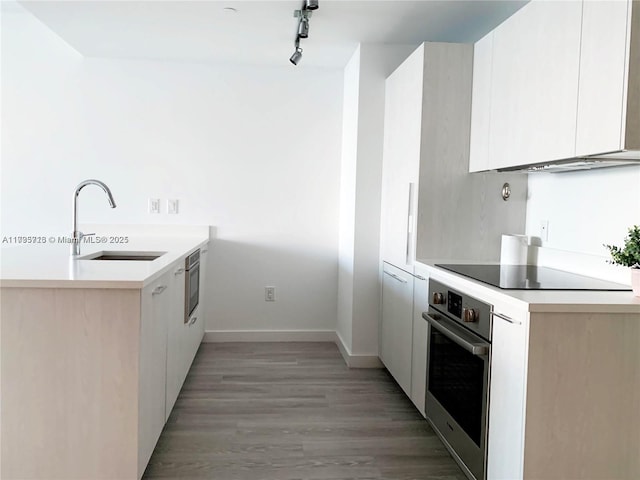 kitchen with sink, white cabinets, stainless steel oven, wall oven, and black electric cooktop