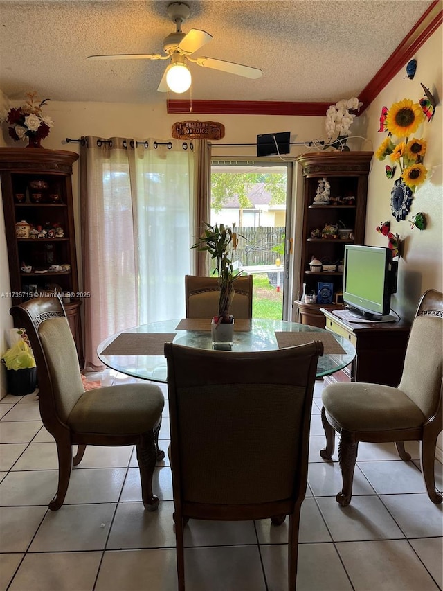 tiled dining room featuring ceiling fan, crown molding, and a textured ceiling