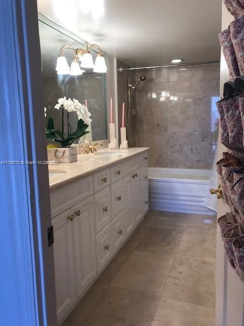 full bath featuring double vanity, tile patterned flooring, washtub / shower combination, and a sink