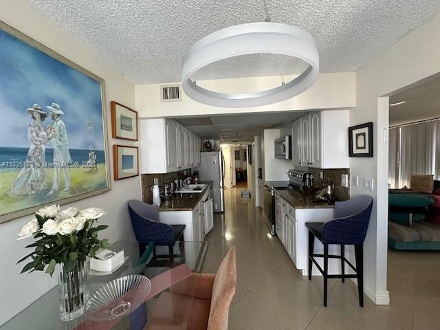 kitchen featuring a sink, stainless steel appliances, dark countertops, and visible vents