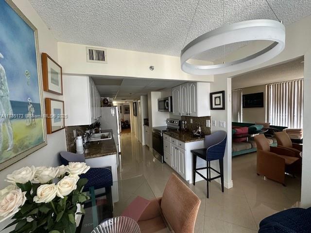 kitchen featuring visible vents, range with electric stovetop, dark countertops, and light tile patterned flooring