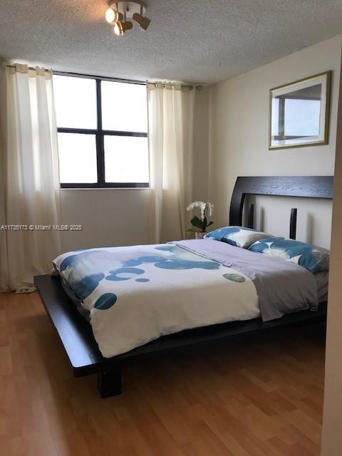 bedroom featuring wood finished floors and a textured ceiling