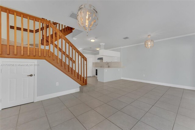 unfurnished living room with sink, ornamental molding, a chandelier, and light tile patterned flooring