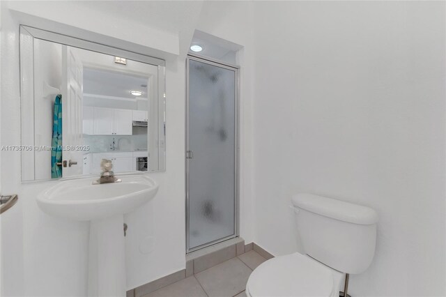 bathroom with toilet, a shower with shower door, and tile patterned flooring