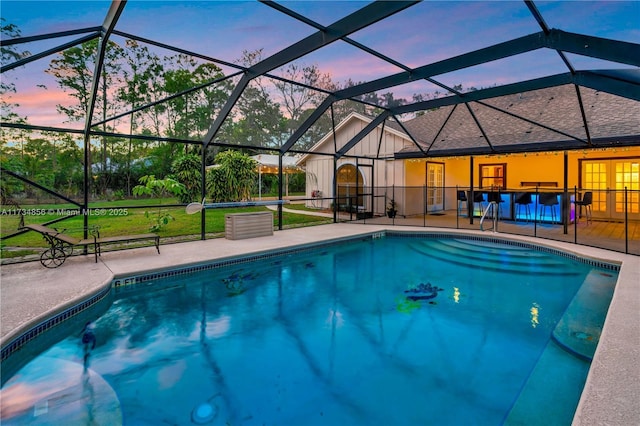 pool at dusk with a patio area and glass enclosure