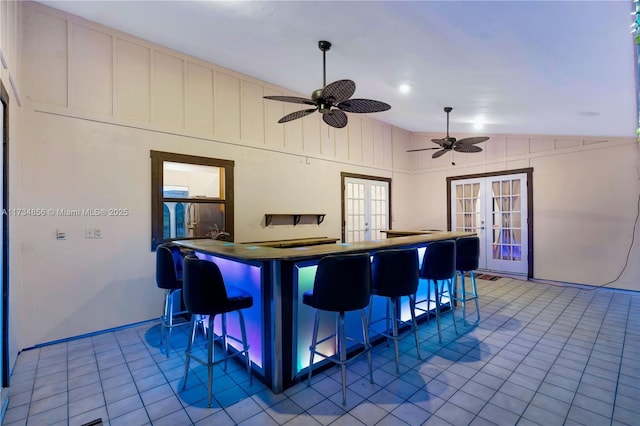 kitchen with french doors, a kitchen bar, vaulted ceiling, light tile patterned floors, and kitchen peninsula