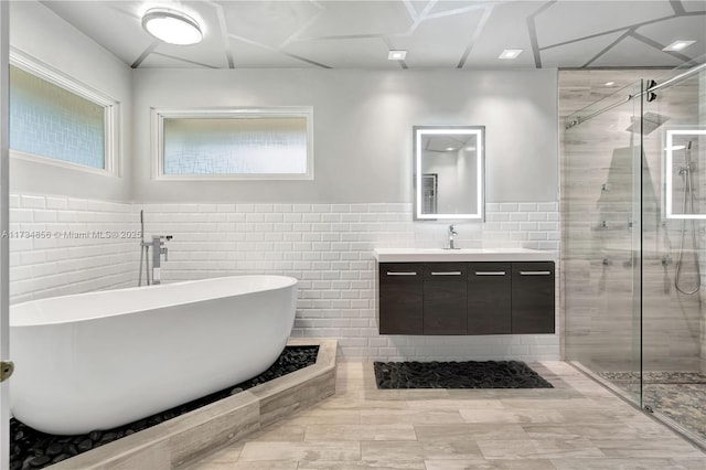 bathroom featuring vanity, tile walls, and plus walk in shower