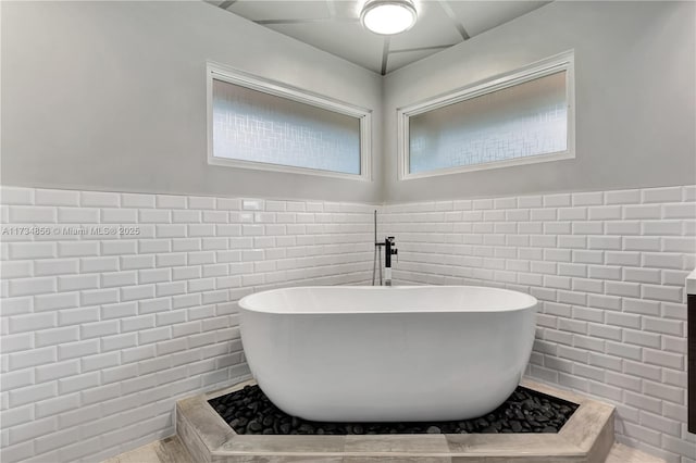 13230 N 153rd Rd N, Jupiter, FL 33478 - bathroom featuring tile walls, a freestanding bath, and a wainscoted wall