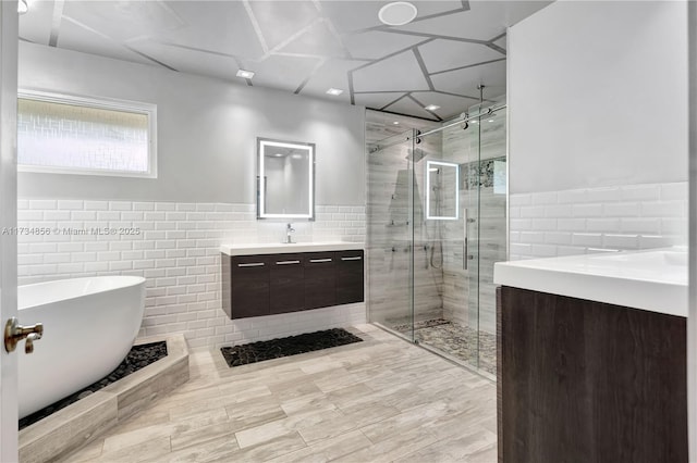 bathroom with vanity, separate shower and tub, and tile walls