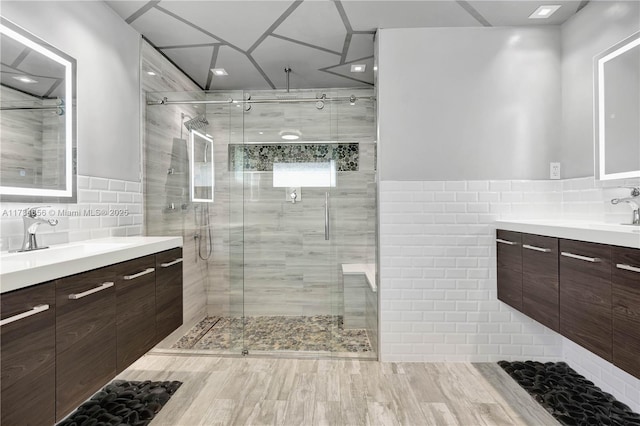 bathroom with a shower with door, vanity, and tile walls