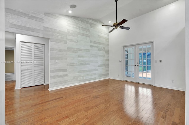 empty room with french doors, ceiling fan, high vaulted ceiling, and hardwood / wood-style flooring