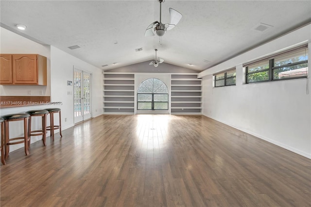 unfurnished living room with dark hardwood / wood-style flooring, a wealth of natural light, a textured ceiling, and built in shelves