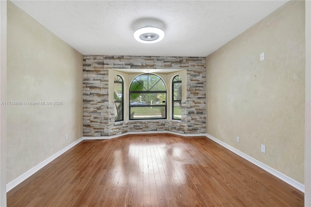 spare room featuring hardwood / wood-style flooring and a textured ceiling