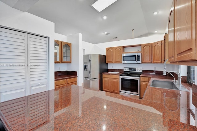 kitchen with lofted ceiling, appliances with stainless steel finishes, kitchen peninsula, and sink