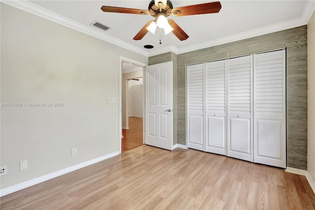 unfurnished bedroom with ornamental molding, light hardwood / wood-style floors, a closet, and ceiling fan