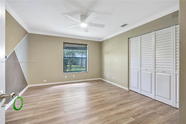 unfurnished bedroom with crown molding, a closet, and light wood-type flooring