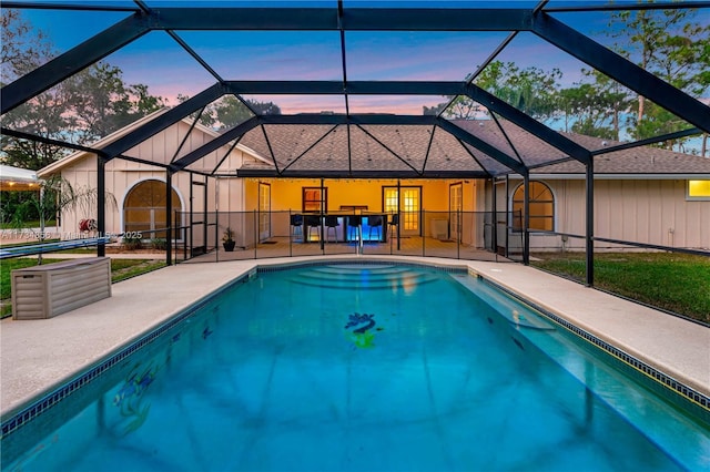 pool at dusk featuring a patio area and glass enclosure