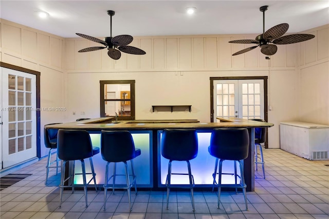 kitchen with a breakfast bar area, fridge, french doors, and ceiling fan