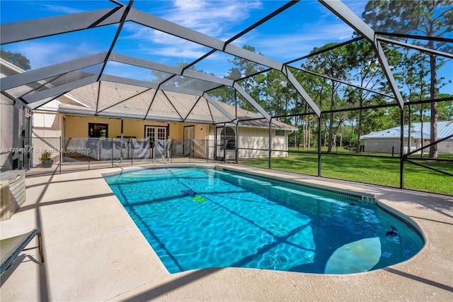 view of pool with a patio, glass enclosure, and a lawn