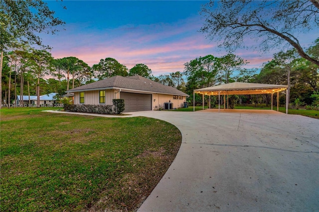 view of front of home with a garage, a lawn, central AC, and a carport